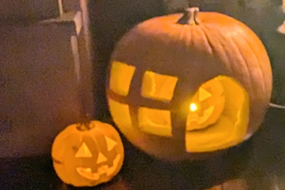 Two carved pumpkins glowing in the dark