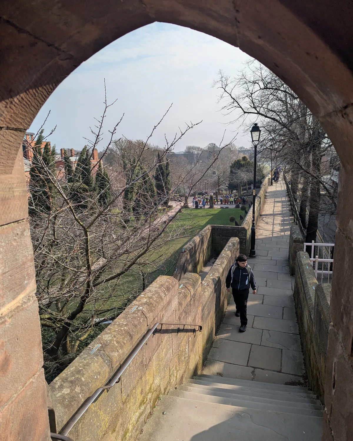 The city walls walk seen through a sandstone archway, with bare winter trees