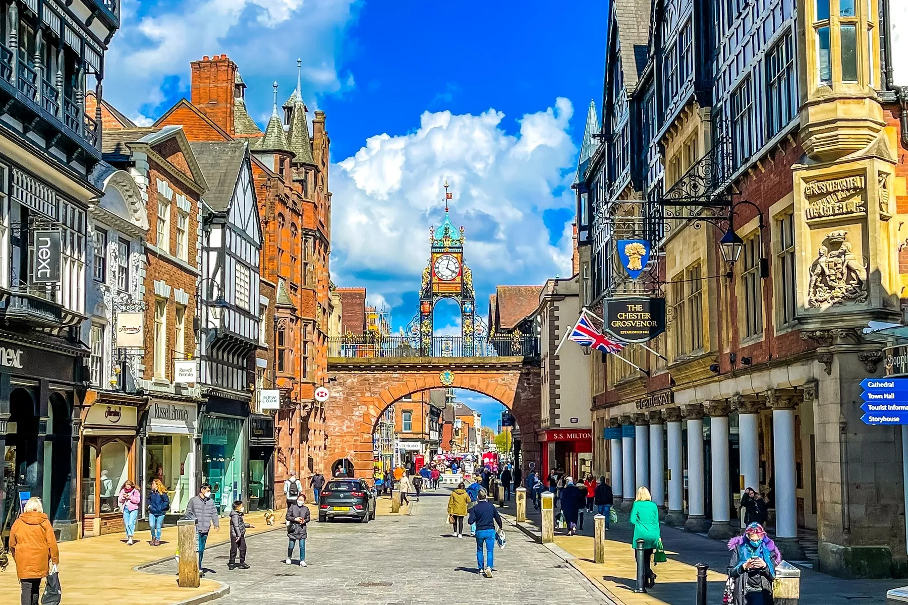 Eastgate Street in Chester on a sunny day, black and white buildings on both sides and the Eastgate Clock on its arch at the far end