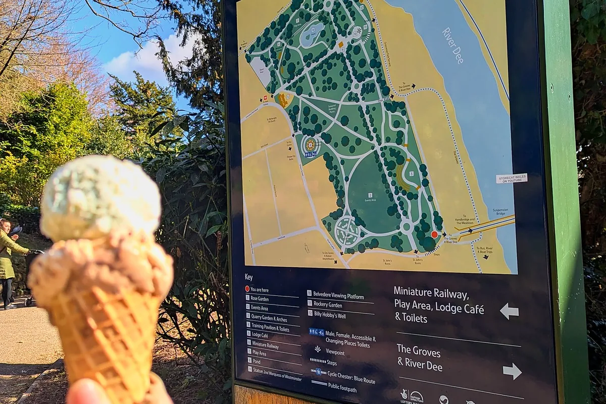 A hand holding an ice cream cone in front of the Grosvenor Park map sign