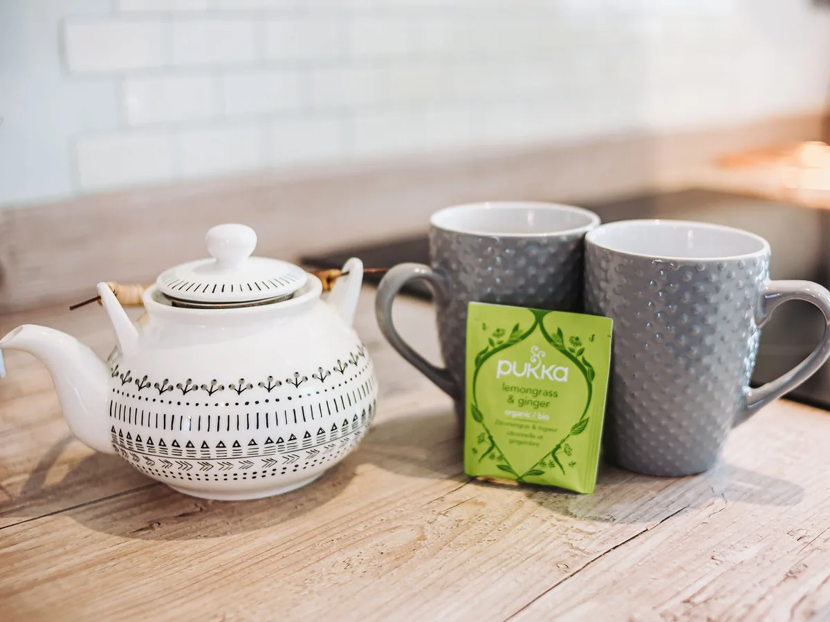 A patterned teapot and two grey mugs on the kitchen worktop