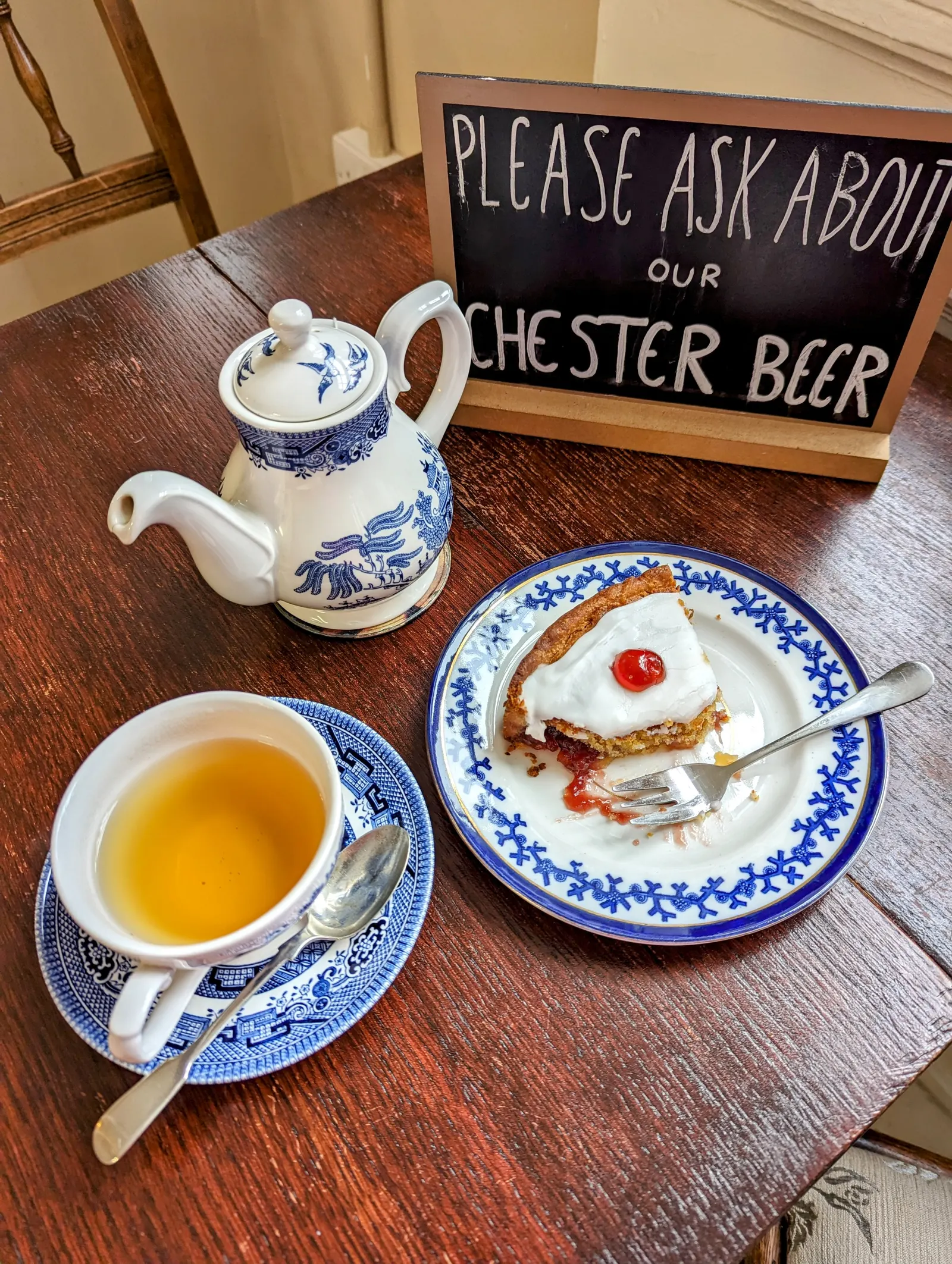 Pot of tea and a slice of cake on blue-and-white china in a Chester cafe