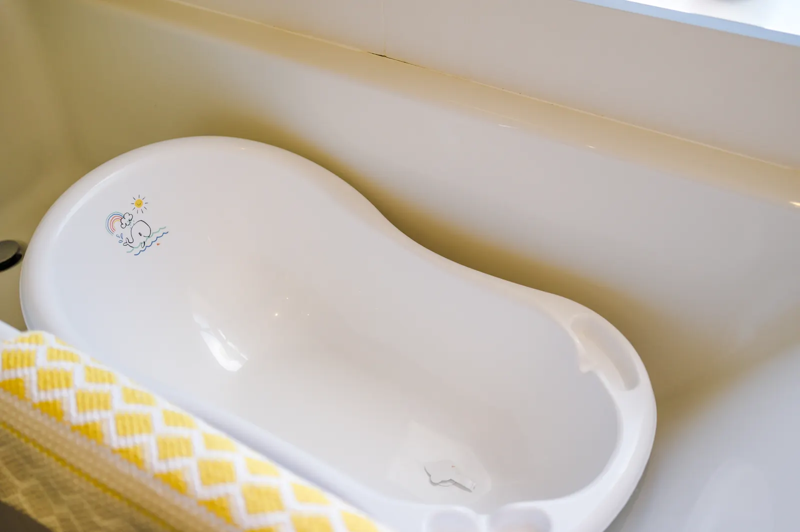 Baby bath with yellow towel ready in the bathroom