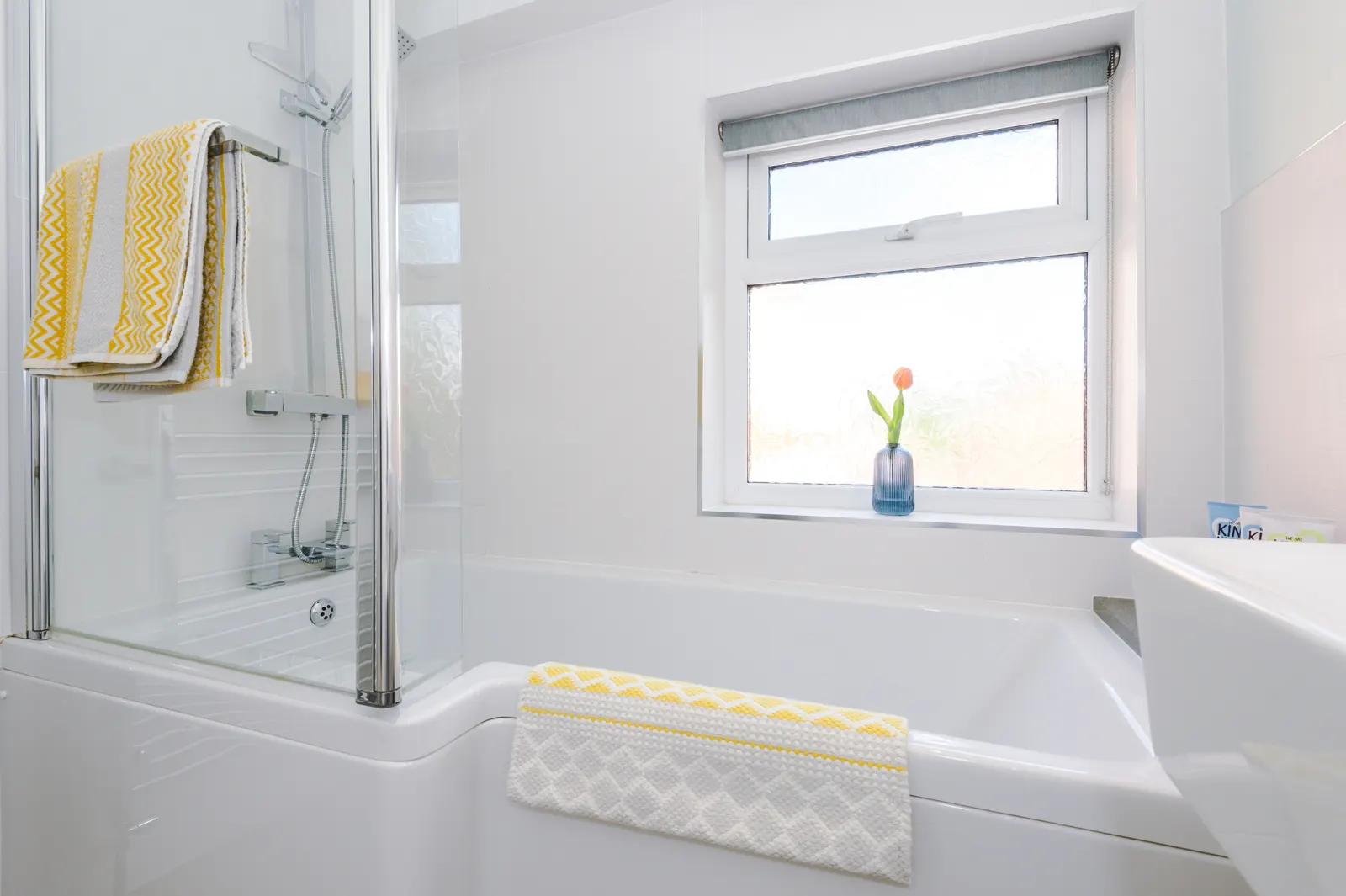 White bathroom with full-size bath, window and yellow towel