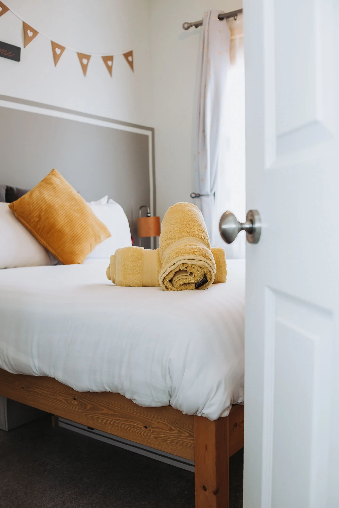 Main bedroom bed made up with soft cushions and a mustard throw