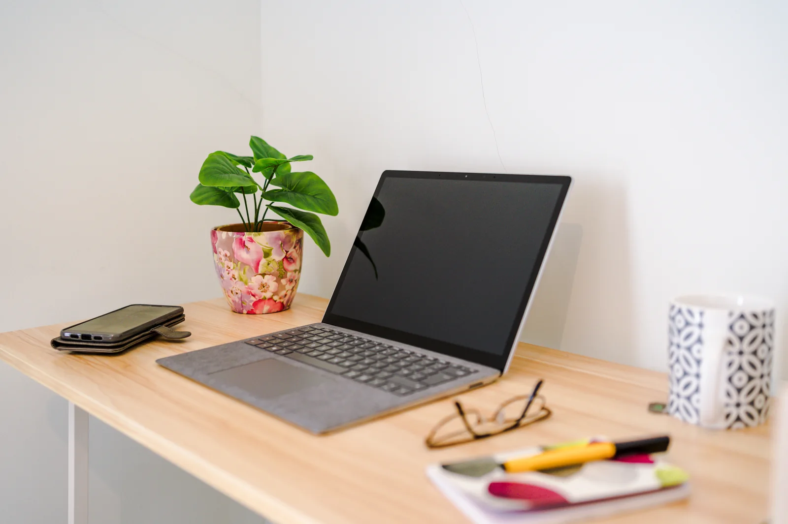 Desk with a laptop, notepad and reading glasses ready for writing