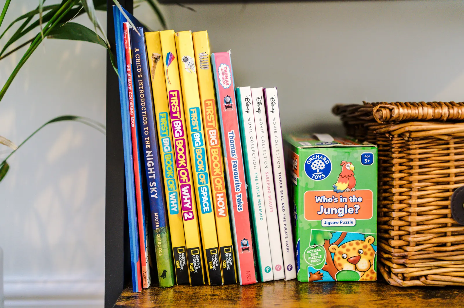 Children's books and games beside a wicker basket
