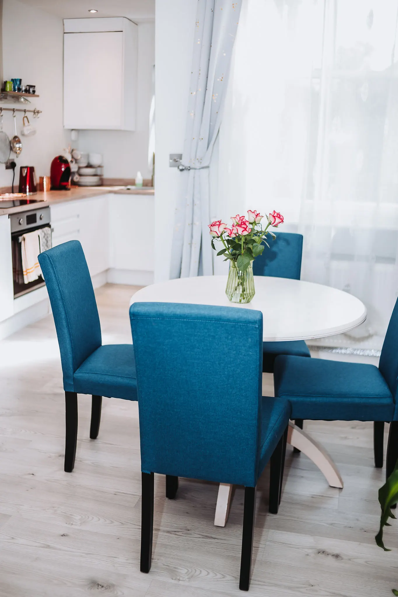 Round dining table with fresh pink flowers and blue chairs