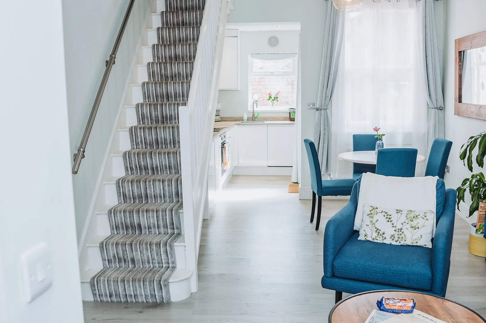 Carpeted staircase and bright hallway leading toward the kitchen and dining space