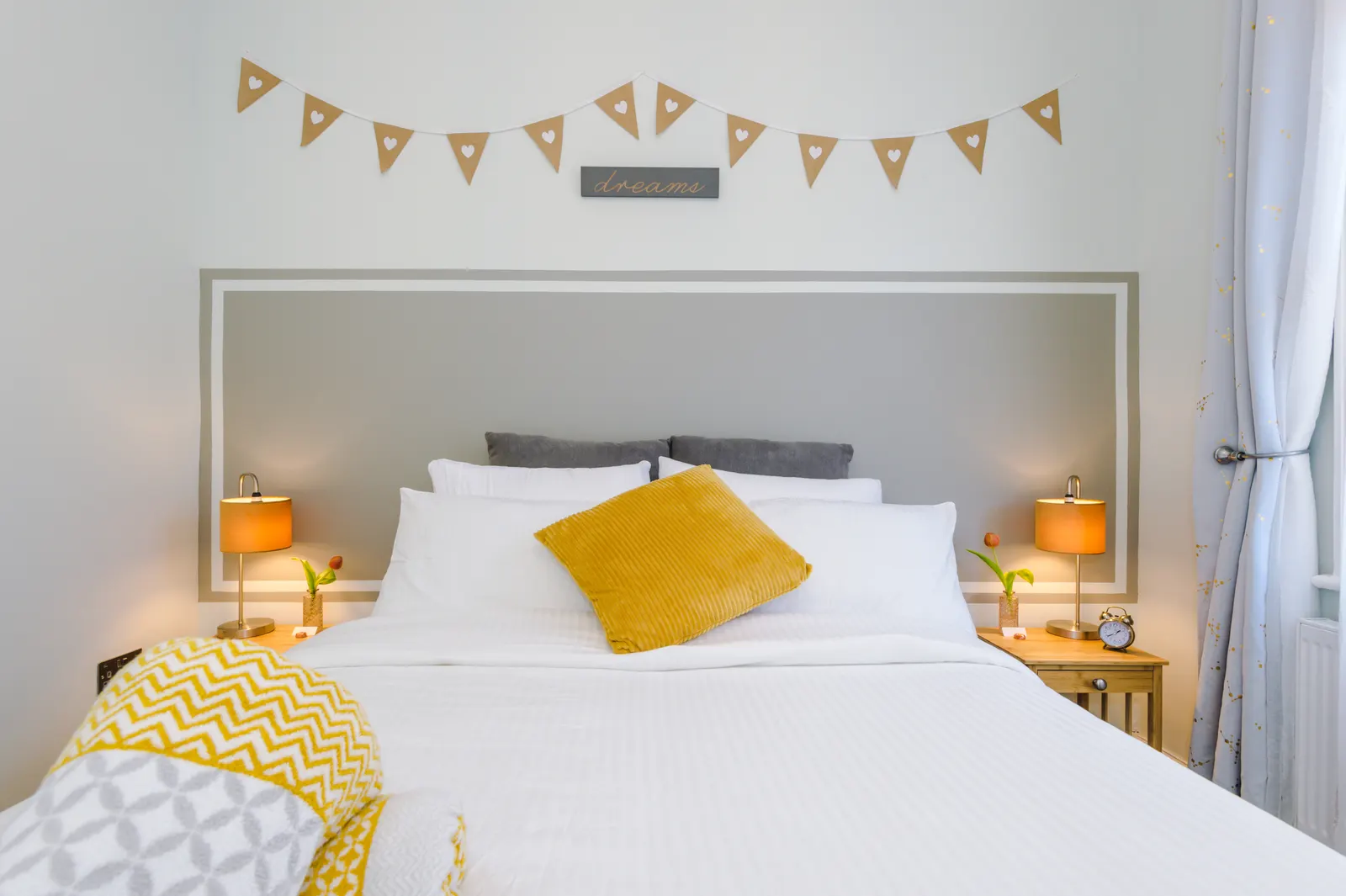 King bedroom with white bedding, mustard cushion and folded throws