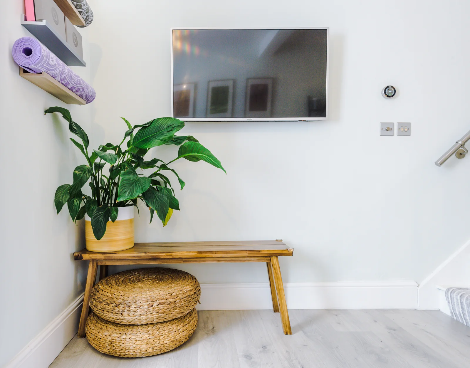 Calm lounge corner with a wooden bench, houseplant and woven floor cushions
