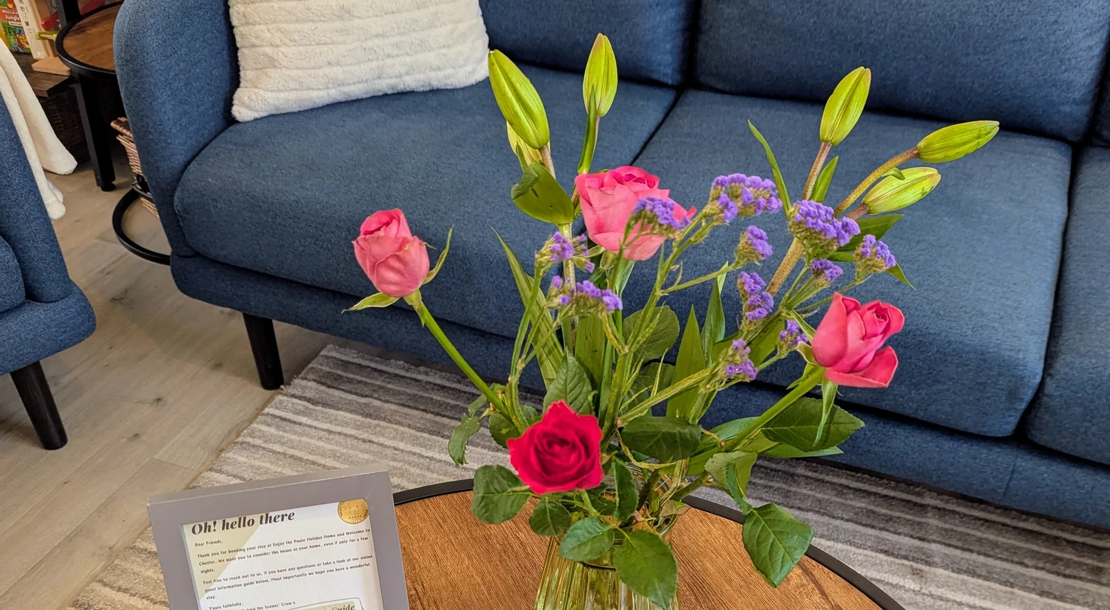 Pink roses and lilies on the lounge coffee table, with the blue sofa and cushions behind