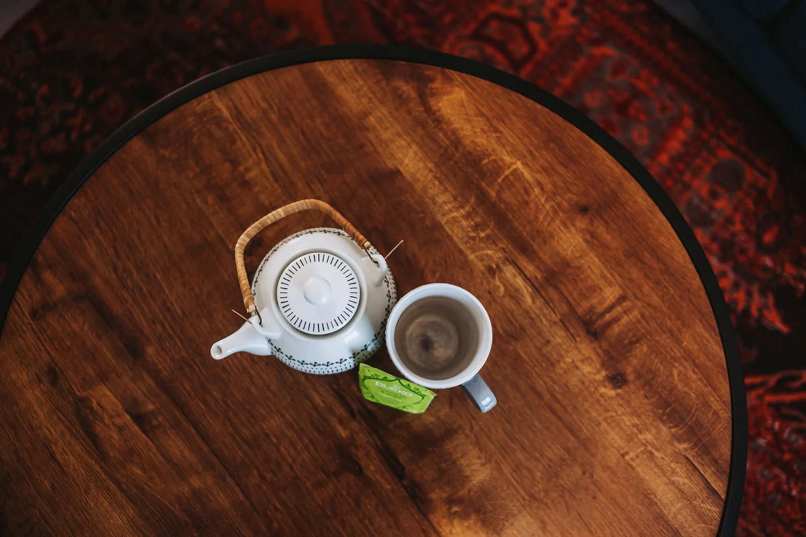 Teapot and mug seen from above on the round wooden lounge table