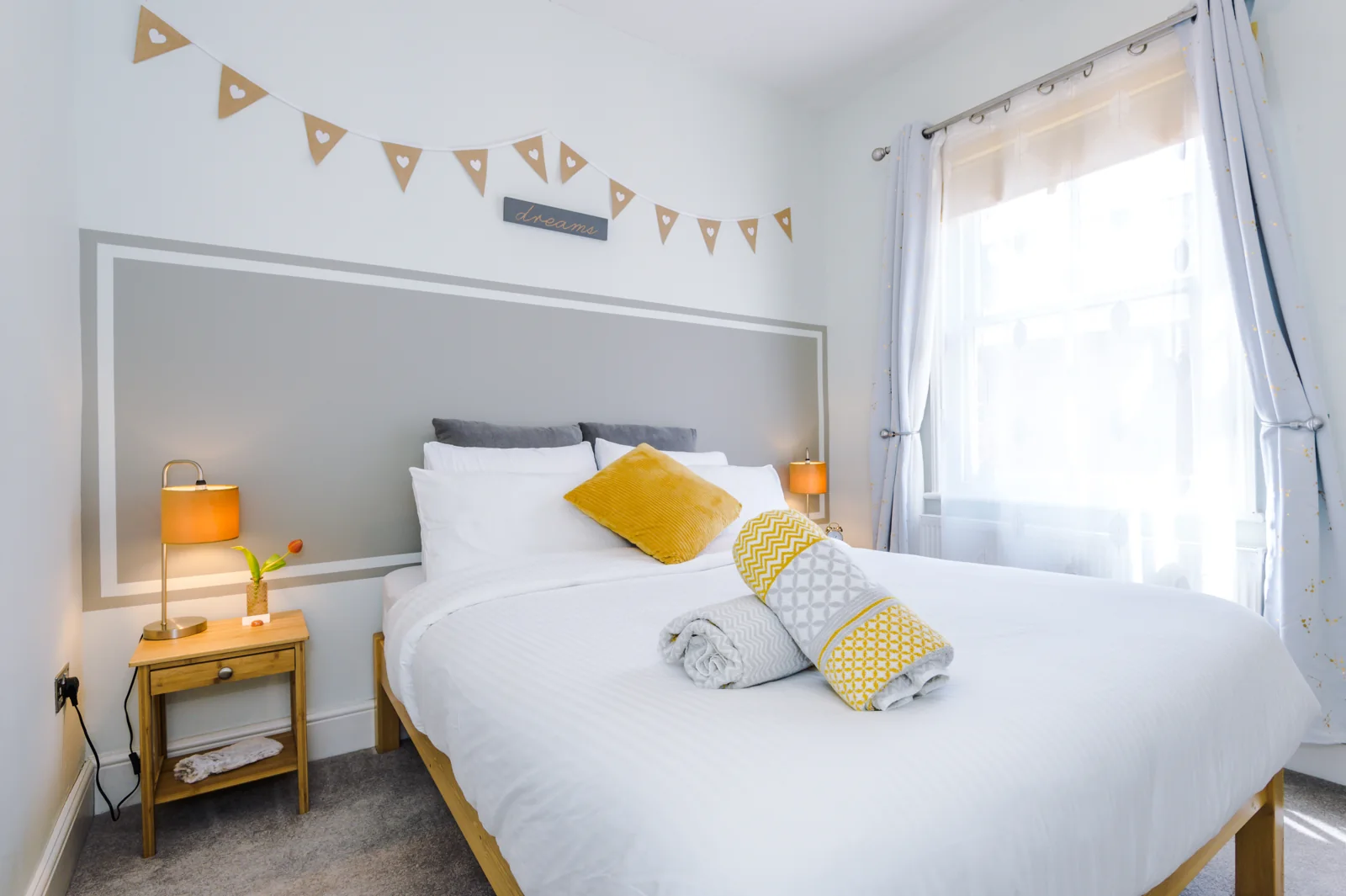 The main bedroom's king bed with soft white bedding and a warm bedside lamp
