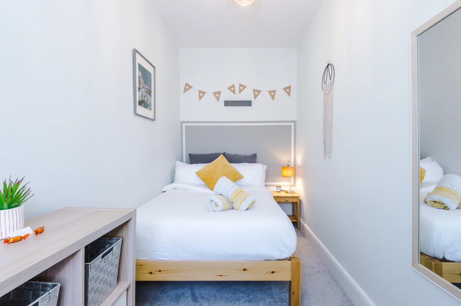 The second bedroom, with shelf storage and a bedside lamp