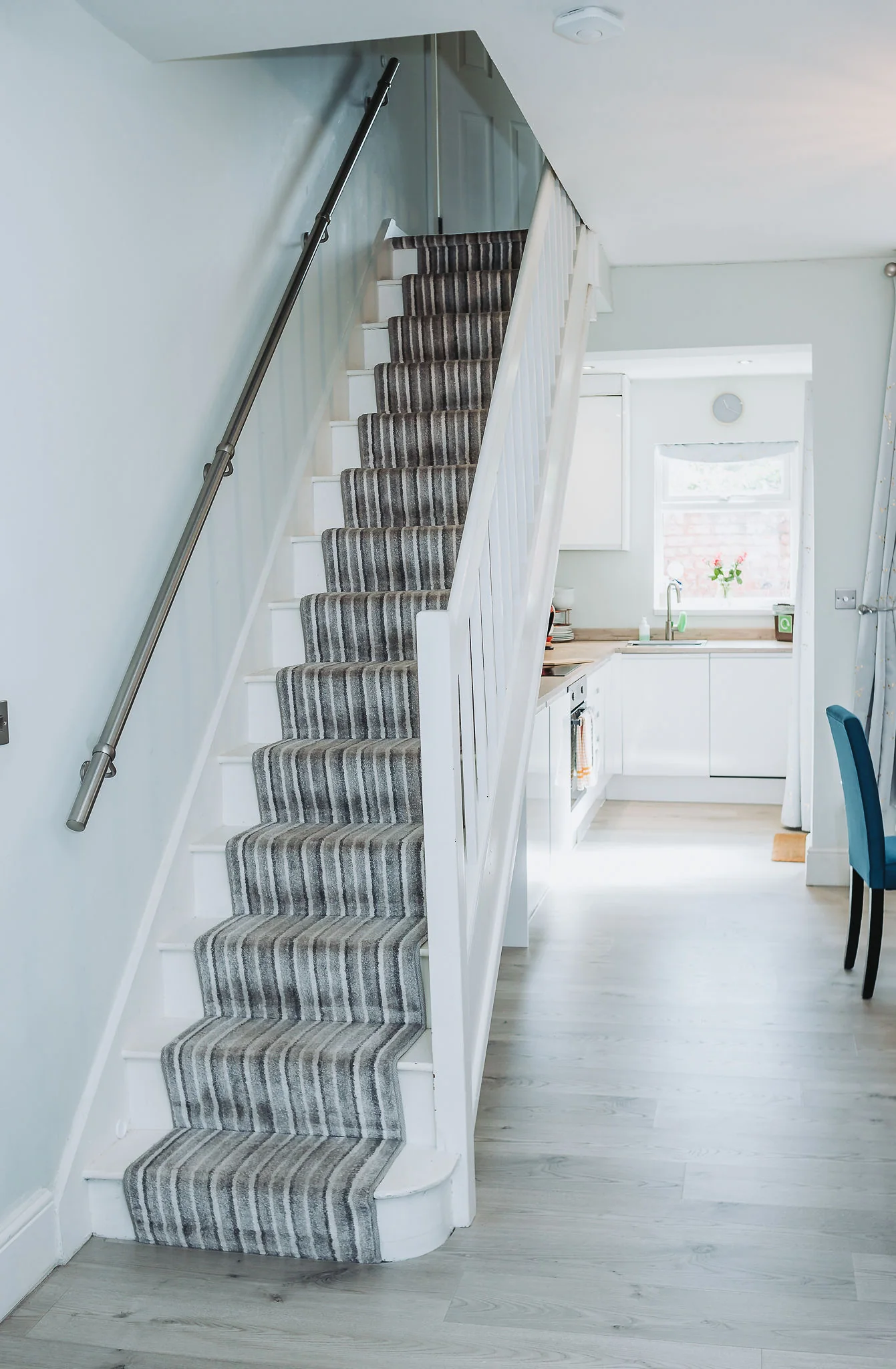 Staircase with striped runner leading down to the kitchen